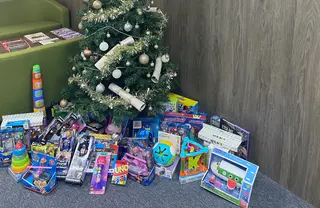 Photo of donated toys sat below a christmas tree
